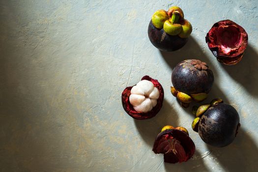 Mangosteen on cement floor and sunlight. Is a seasonal fruit in Thailand. Top view and copy space for text.