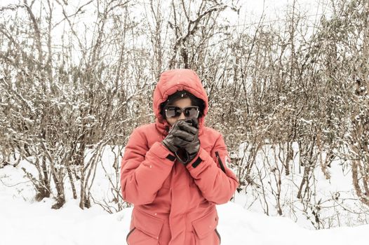 Smiling happy joyful Portrait of a Woman wearing a red pullover jacket and gloves enjoying first snow while shakes off snowball. Enjoy Snowing day view in winter. Rural village Jammu and Kashmir India