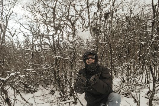 Smiling happy joyful Portrait of a Man wearing a black pullover jacket enjoying first snow playing and throwing snowball in air. Enjoy Snowing day view in winter. Rural village Jammu and Kashmir India