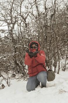 Smiling happy joyful Portrait of a Woman wearing a red pullover jacket enjoying first snow playing and throwing snowball in air. Enjoy Snowing day view in winter. Rural village Jammu and Kashmir India