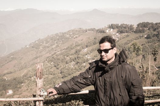 Close-up Portrait of a stylish asian handsome man in winter clothes, stands sideways on a background snow mountain. An attractive mature adult in trendy outfit. Perfect wintertime lifestyle image.