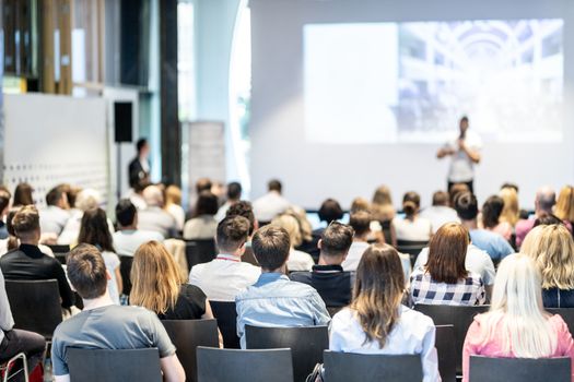 Audience at the conference hall. Male speaker giving a talk in conference hall at business event. Business and Entrepreneurship concept. Focus on unrecognizable people in audience.