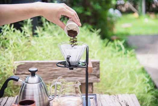 Man making drip fresh coffee in vintage coffee shop with green nature background - people with fresh coffee in nature concept