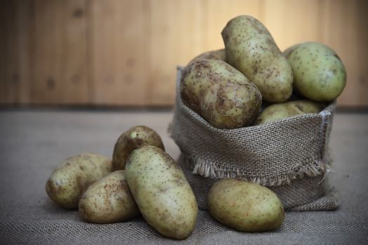 Fresh potato ready for cooking with potato sack background - potato cooking concept