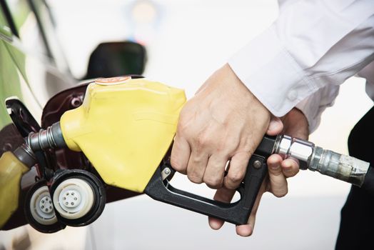 Man putting gasoline fuel into his car in a pump gas station