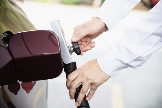 Man is putting NGV, Natural Gas Vehicle, head dispenser to a car at the gasoline station in Thailand