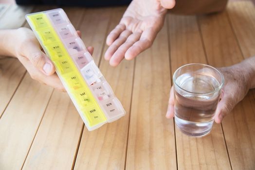 Doctor is assist patient to eat medicine tablet in pillbox correctly - people medical concept