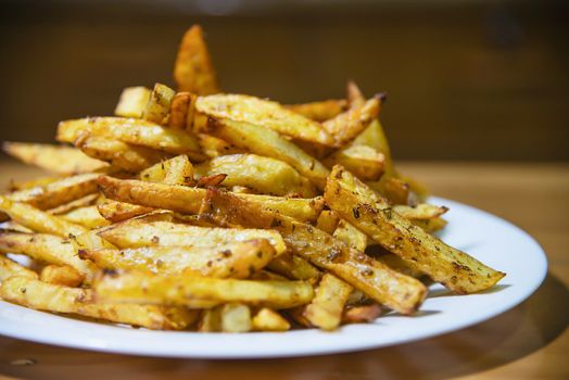 Delicious French fried potato mix with chilly powder on wooden table - traditional fast food concept