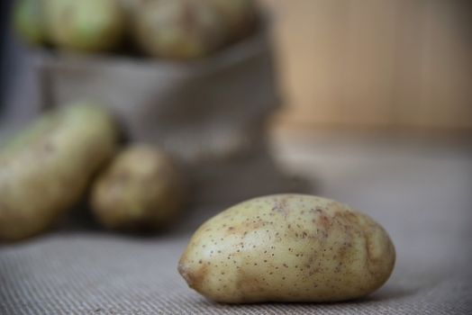 Fresh potato ready for cooking with potato sack background - potato cooking concept