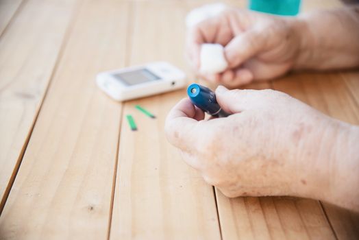 Old lady is testing blood sugar level using blood sugar test kid set - people with medical equipment concept