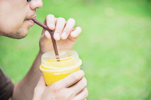 Man drink ice mango orange blend in green garden - relax people with cold fruit drink concept
