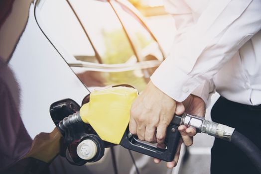 Man putting gasoline fuel into his car in a pump gas station