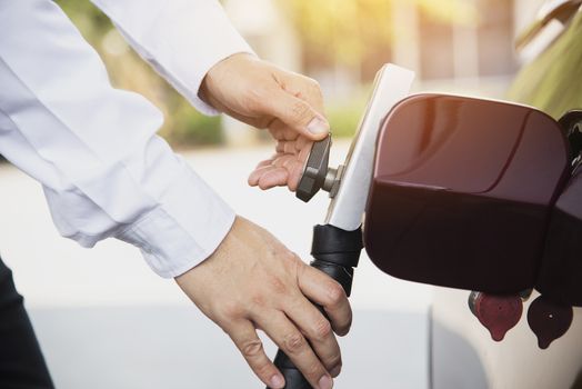 Man is putting NGV, Natural Gas Vehicle, head dispenser to a car at the gasoline station in Thailand