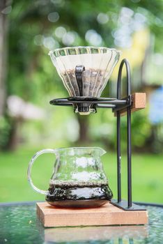 Making drip coffee in vintage coffee shop with green garden nature background - fresh coffee in nature concept