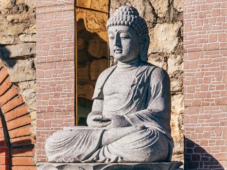 White stone statue of a Buddha on masonry background