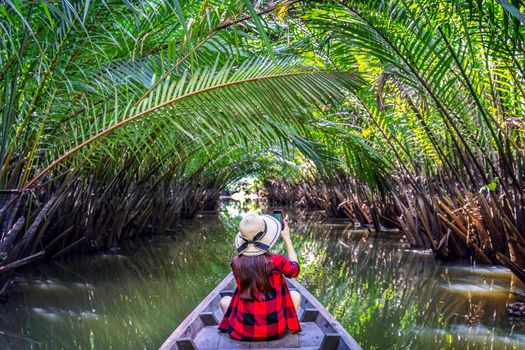 Asian women sitting on a boat at tunnel from nypa fruticans or palm tree in Surat thani,Thailand.