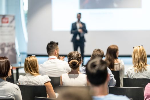 Male speaker giving a talk in conference hall at business event. Audience at the conference hall. Business and Entrepreneurship concept. Focus on unrecognizable people in audience.