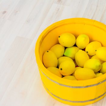 large yellow lemons in a large yellow wooden basin standing on the floor