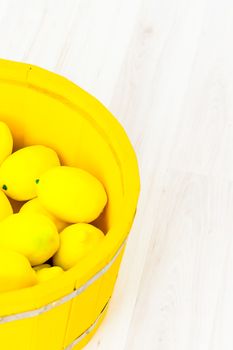 large yellow lemons in a large yellow wooden basin standing on the floor