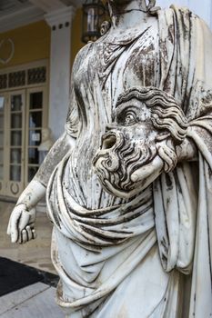 Achilleion palace, Corfu, Greece - August 24, 2018: A tragic mask in the hand of Statue of Melpomene, the muse of tragedy, on the balcony of Achillion palace on greek island Corfu in Greece.