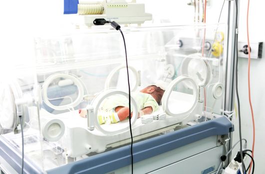 Newborn baby in hospital incubator.