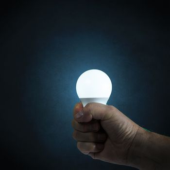 a light bulb on in hand with an antique blue background