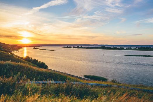 River shore in the sunset light. Blue cloudy sky.