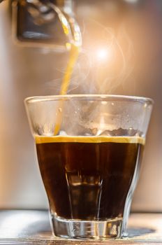 Barista making a espresso with a classic coffee machine with steam in background.