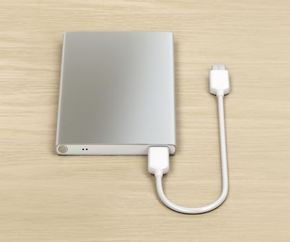 Silver power bank with usb-c cable on wood table