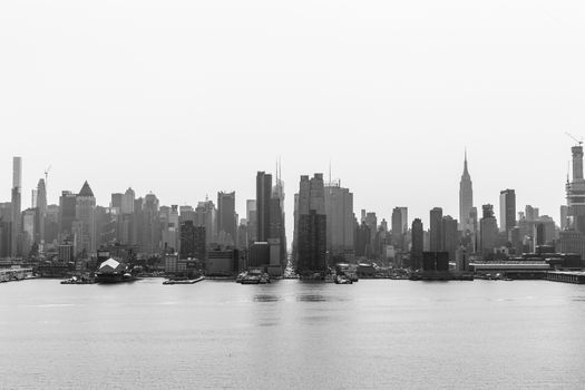 New York City midtown Manhattan skyline panorama view from Boulevard East Old Glory Park over Hudson River on a misty morning. Black and white image.