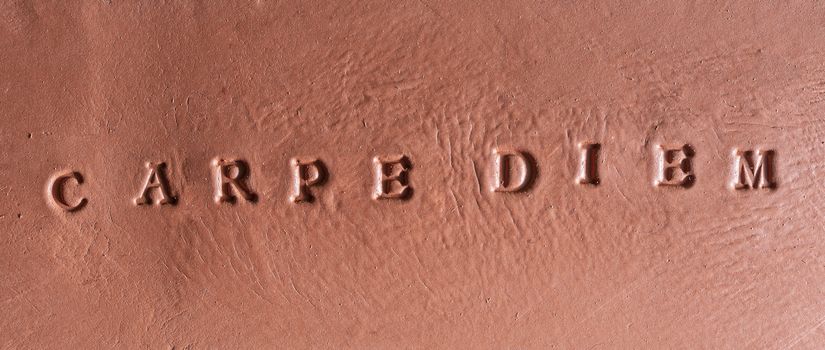  the phrase  “Carpe diem” written in Latin on a terracotta tablet