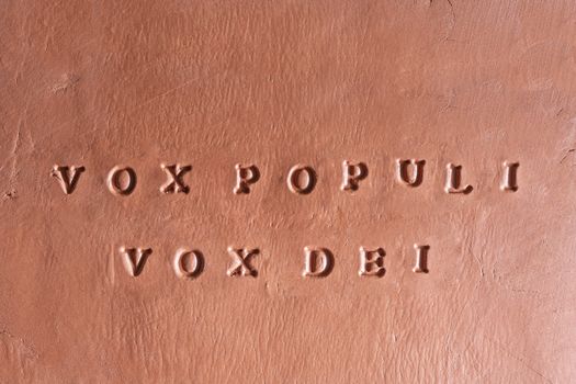  the phrase  “Vox populi vox Dei” written in Latin on a terracotta tablet