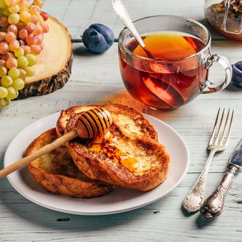 Healthy breakfast concept. French toasts with honey, fruits and tea over white wooden background