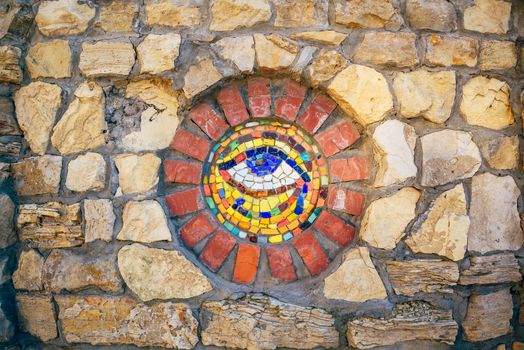 Circular mosaic symbol Eye of Horus on stone wall.