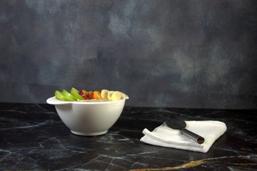 Healthy breakfast, a cup of oatmeal with slices of fruit and a spoon on a white napkin.