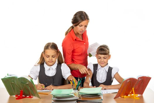 The teacher helps schoolgirls in the lesson, prompting how to solve the problem