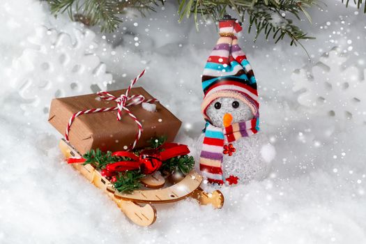 Christmas composition under the Christmas tree - a snowman, boxes with gifts on a sled and other decorations, place for text, copy space.