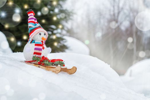 Snowman slides downhill on a sled - winter and Christmas fun concept, place for text, copy space.