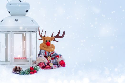 Christmas composition - deer, lantern with a burning candle and decorations under the Christmas tree.