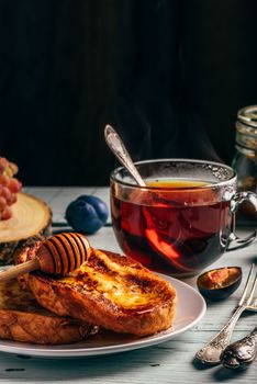 Healthy breakfast concept. French toasts with honey, fruits and tea over white wooden background