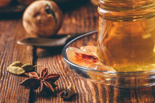 Arabic tea with star anise, cardamom and dried lime in oriental glass over wooden surface