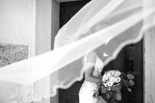 The Kiss. Bride and groom kisses tenderly in the shadow of a flying veil. Close up portrait of sexy stylish wedding couple kissing under white vail. Artistic black and white wedding photo.