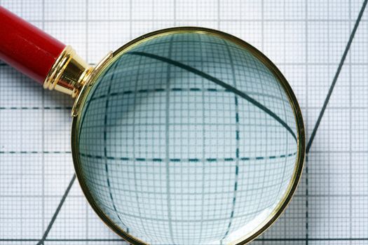 Closeup of magnifying glass on paper background with graph