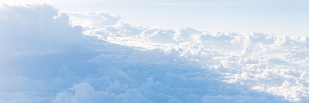 Panorama beautiful and unusual Altocumulus or Cirrocumulus cloud formation seen from airplane window at sunrise. Skyline view above the clouds from the air