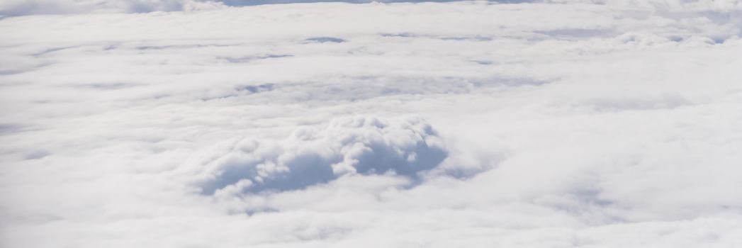 Panorama beautiful and unusual Altocumulus or Cirrocumulus cloud formation seen from airplane window at sunrise. Skyline view above the clouds from the air