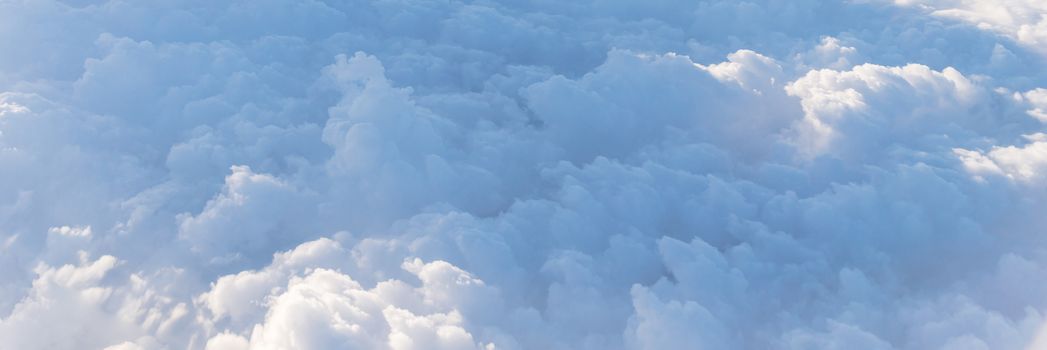 Panorama beautiful and unusual Altocumulus or Cirrocumulus cloud formation seen from airplane window at sunrise. Skyline view above the clouds from the air