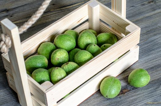 Young fruits of walnuts in a green shell in a wooden box