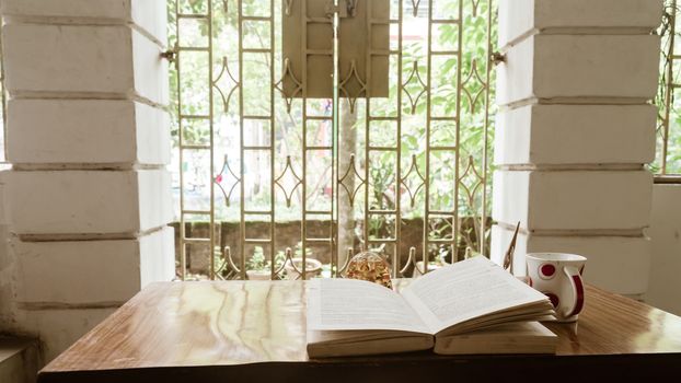 Coffee and book by window on a sunday morning. Reading book in morning sunlight. Hygge summer mood. Holidays, leisure, literature and relaxation concept.