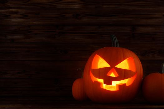 Glowing Halloween pumpkin heads jack o lantern on wooden background