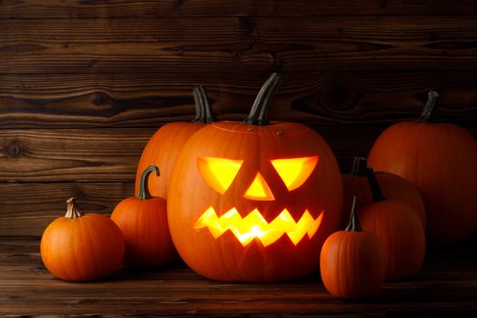 Glowing Halloween pumpkin heads jack o lantern on wooden background